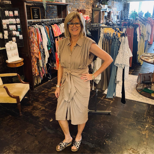 owner dressed in a fashionable tan wrap dress 